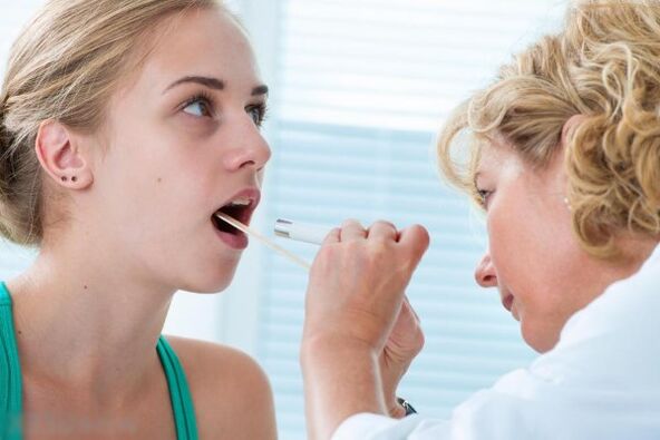 Lægen undersøger mundhulen for tilstedeværelsen af ​​papillomer